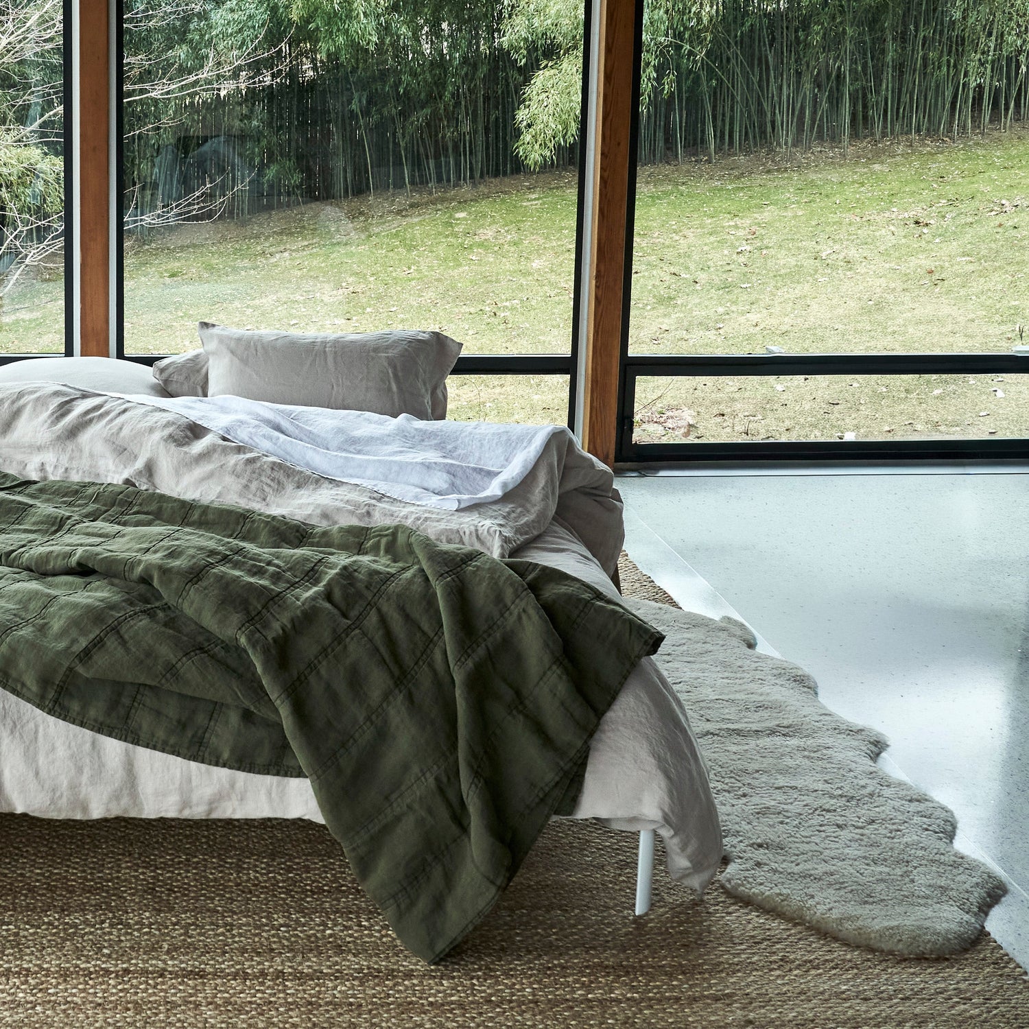 Bedroom with large windows offering a view of trees and greenery