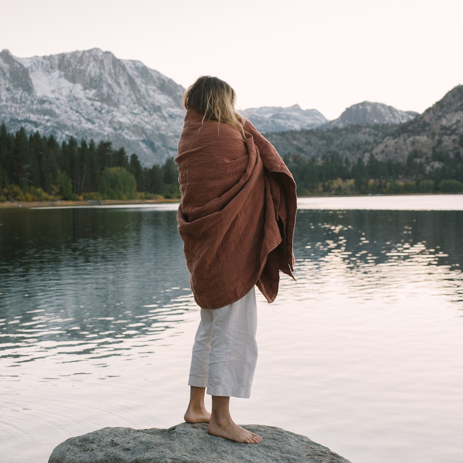 Woman wrapped in Evenfall Hemp Quilt, Daybreak in Terracotta