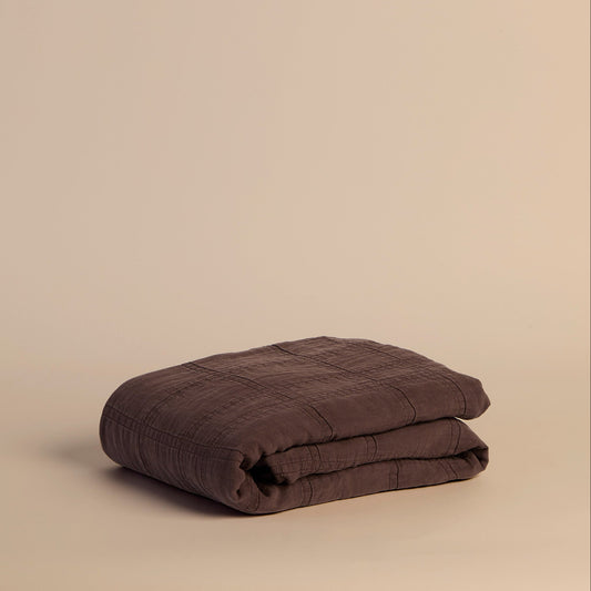 Folded muted purple blanket on a beige background