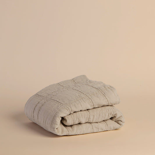 Folded grayish beige blanket on a beige background