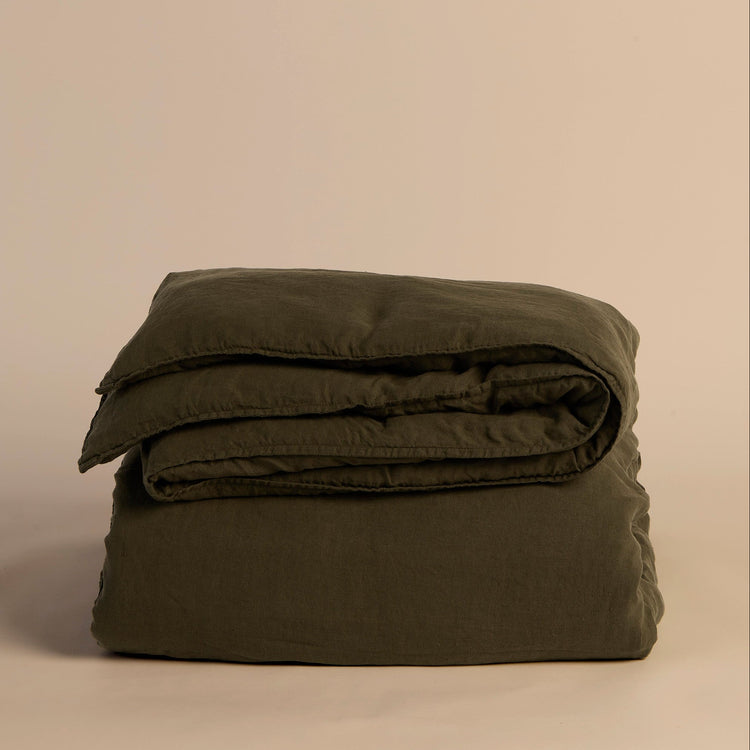 Folded green duvet cover and comforter on a beige background