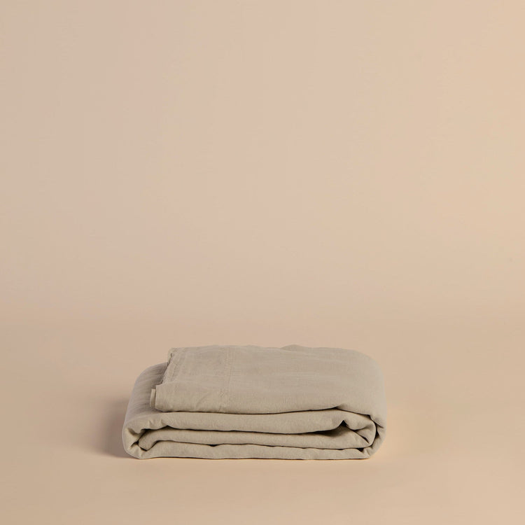 Folded beige flat sheet blanket on a beige background
