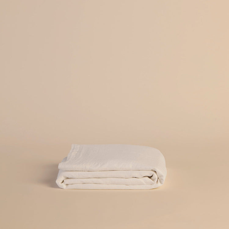 Folded white flat sheet on a beige background