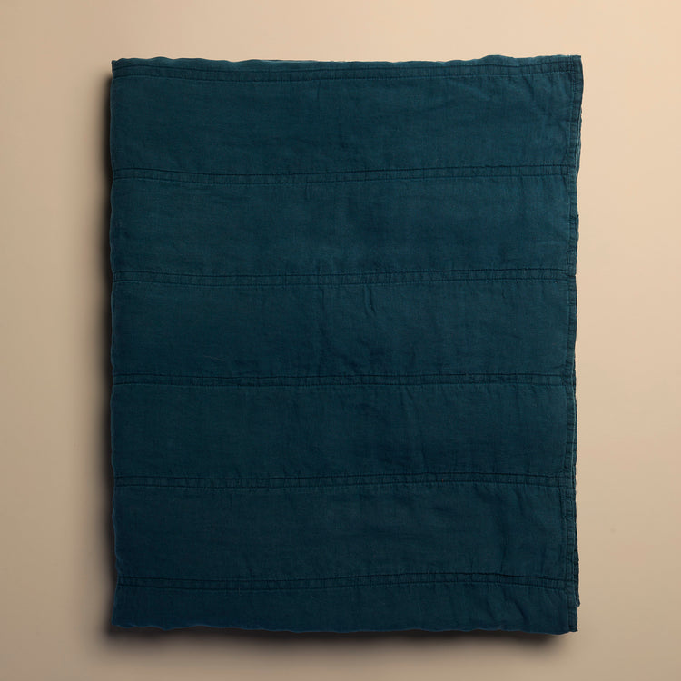 Folded dark blue quilt on a beige background