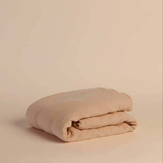 Folded peach quilt on a beige background