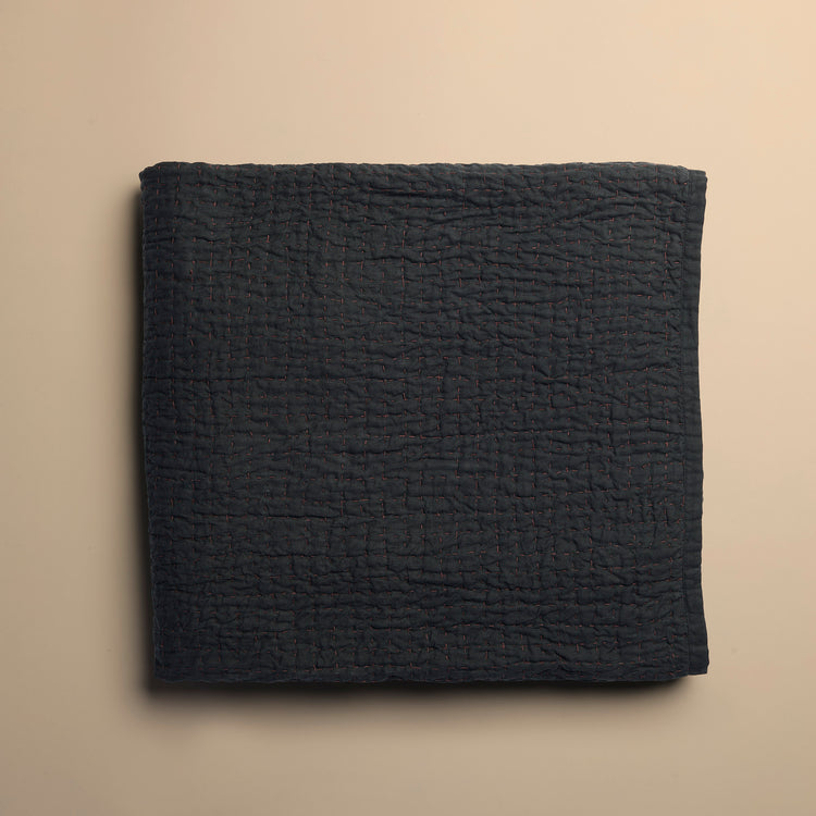 Folded dark blue textured blanket on a beige background