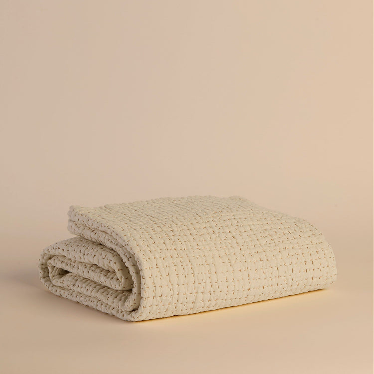 Folded ivory textured blanket on a beige background