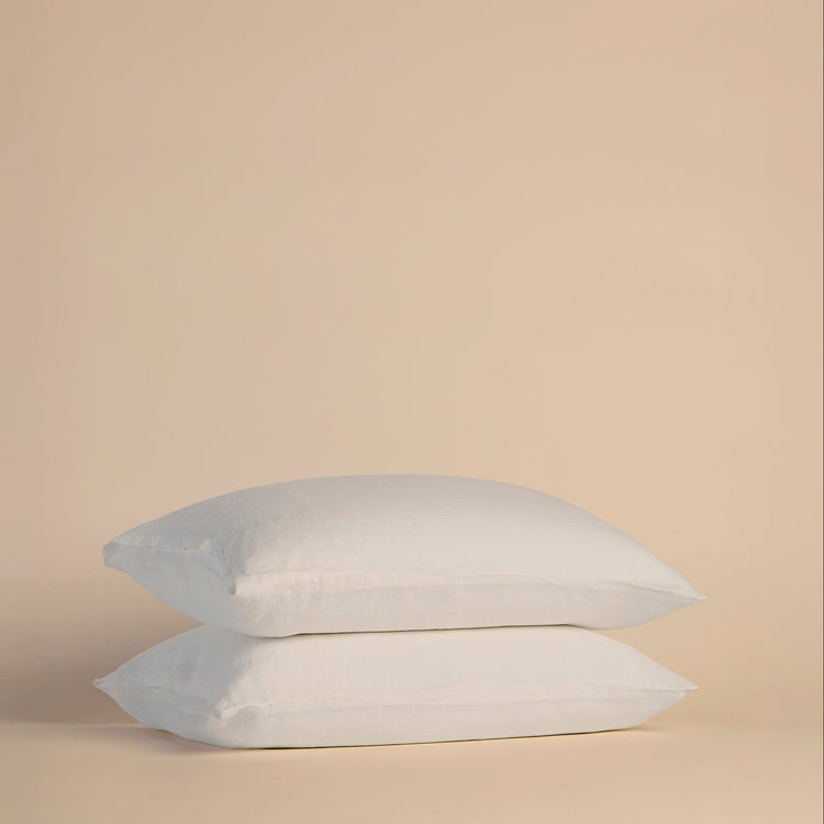Two white pillows with pillowcases on a beige background