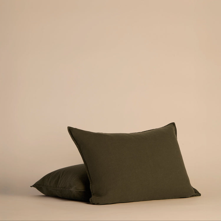 Two dark green shams and pillows on a beige background