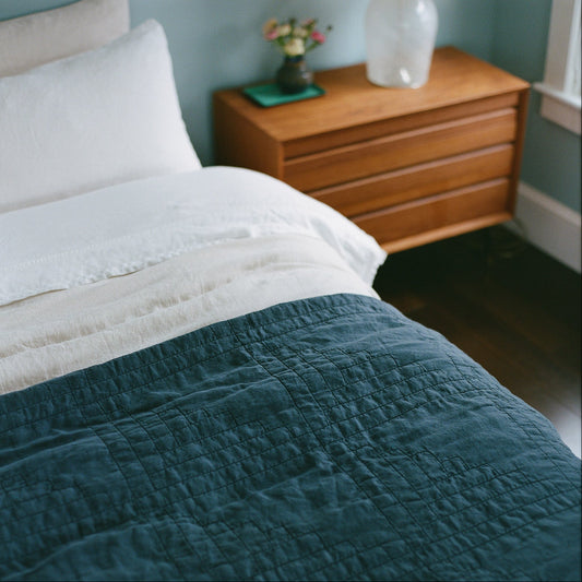 Midnight blue quilt on a bed with a wooden nightstand in the background