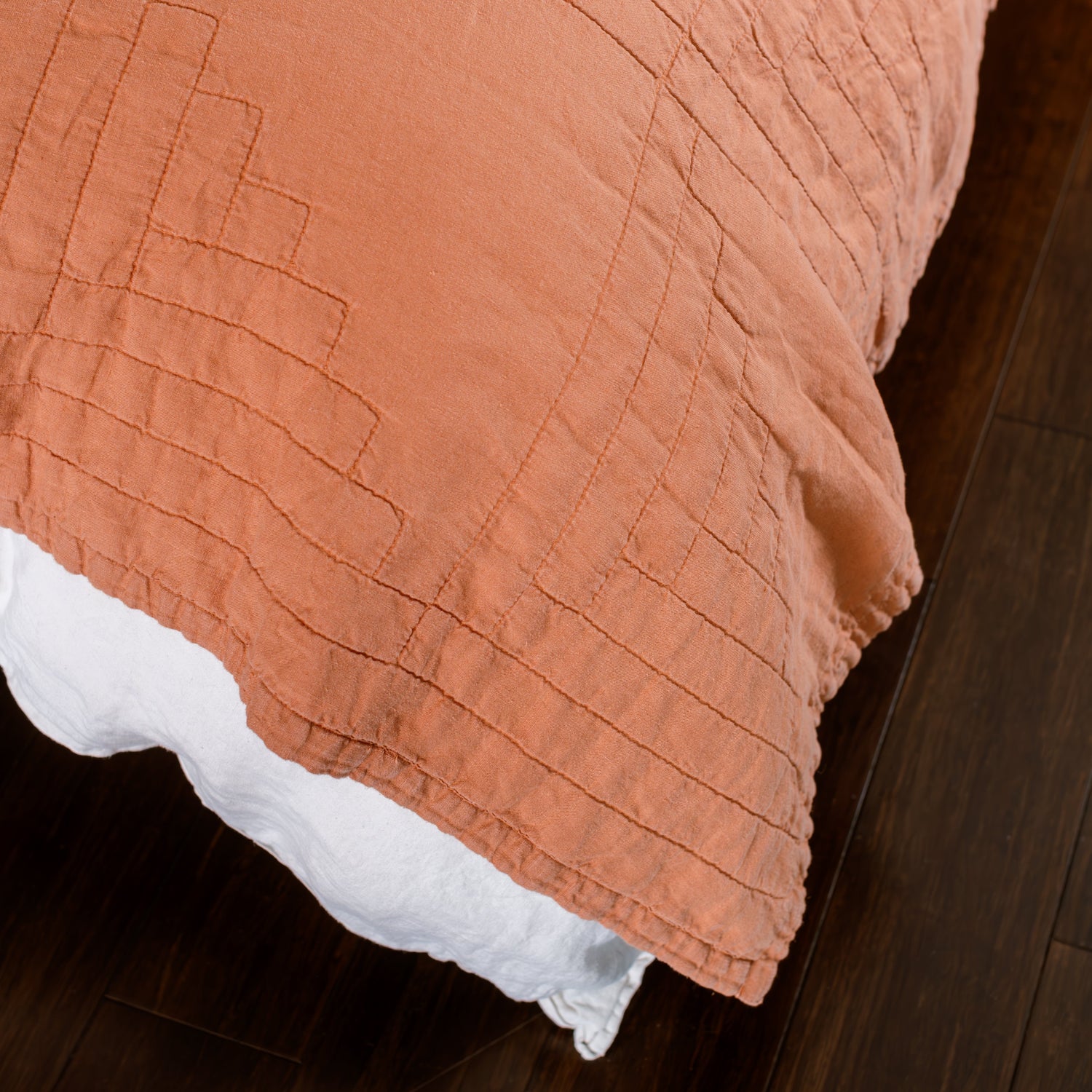 Close-up of a textured orange bedspread on a wooden bed frame.