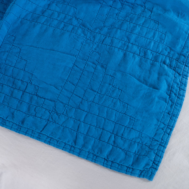Bright blue textured quilt on a white background