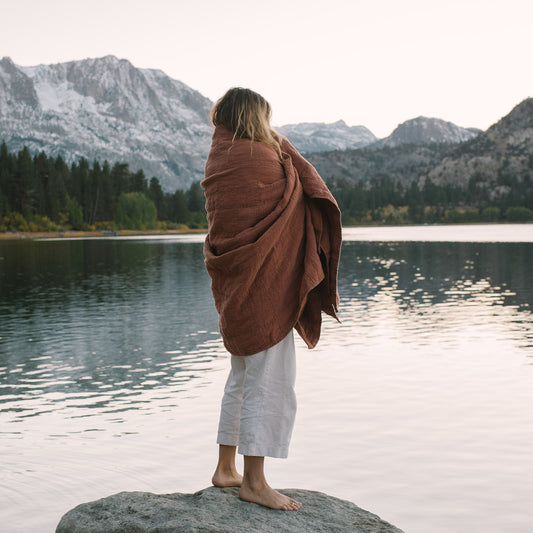 Woman wrapped in Evenfall Hemp Quilt, Daybreak in Terracotta