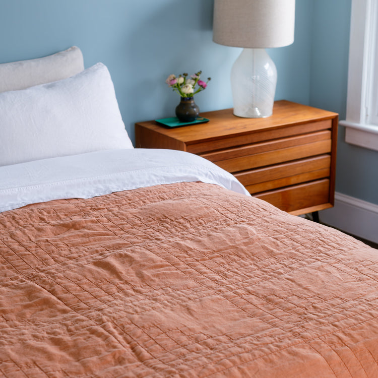 Bed with copper quilt and wooden nightstand in a bedroom setting