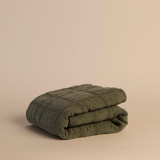 Folded green quilt on a beige background