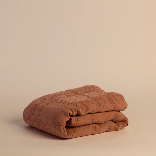 Folded brick red blanket on a beige background