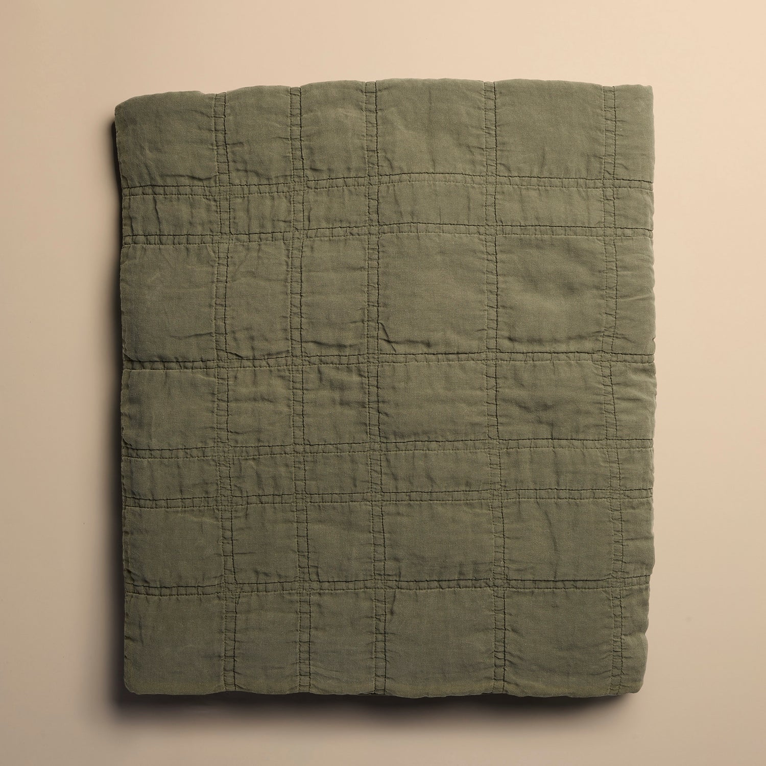 Folded green quilt on a beige background