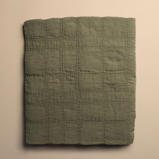 Folded green quilt on a beige background