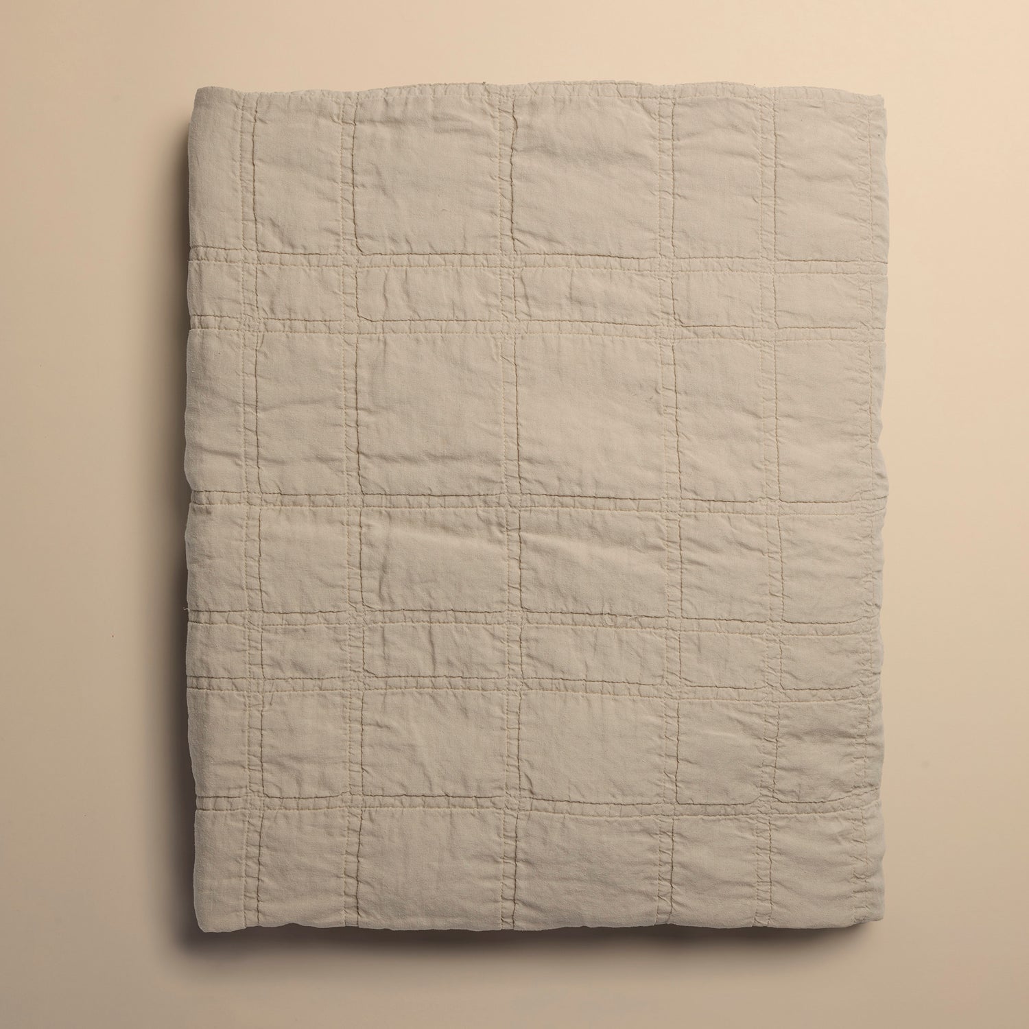 beige quilt folded on beige background