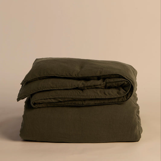 Folded green duvet cover and comforter on a beige background