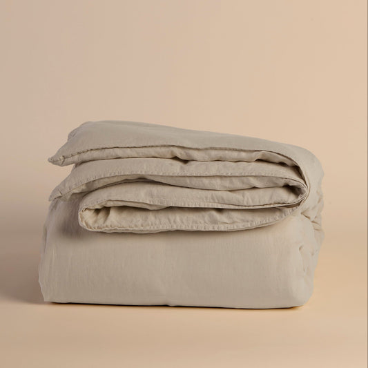 Folded light beige duvet cover and comforter on a beige background