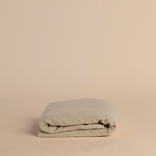 Folded beige flat sheet on a beige background