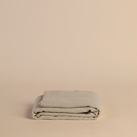 Folded beige flat sheet blanket on a beige background