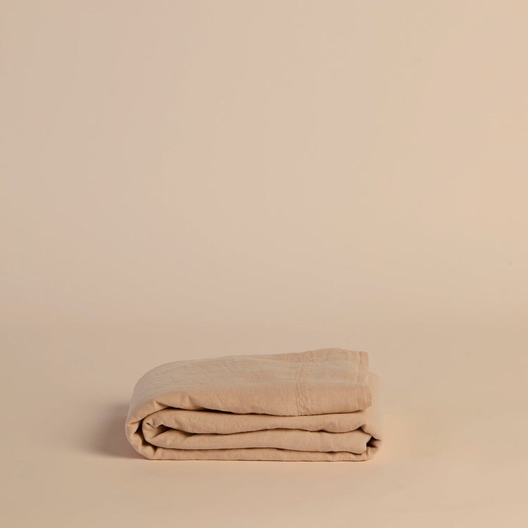 Folded peach flat sheet on a beige background