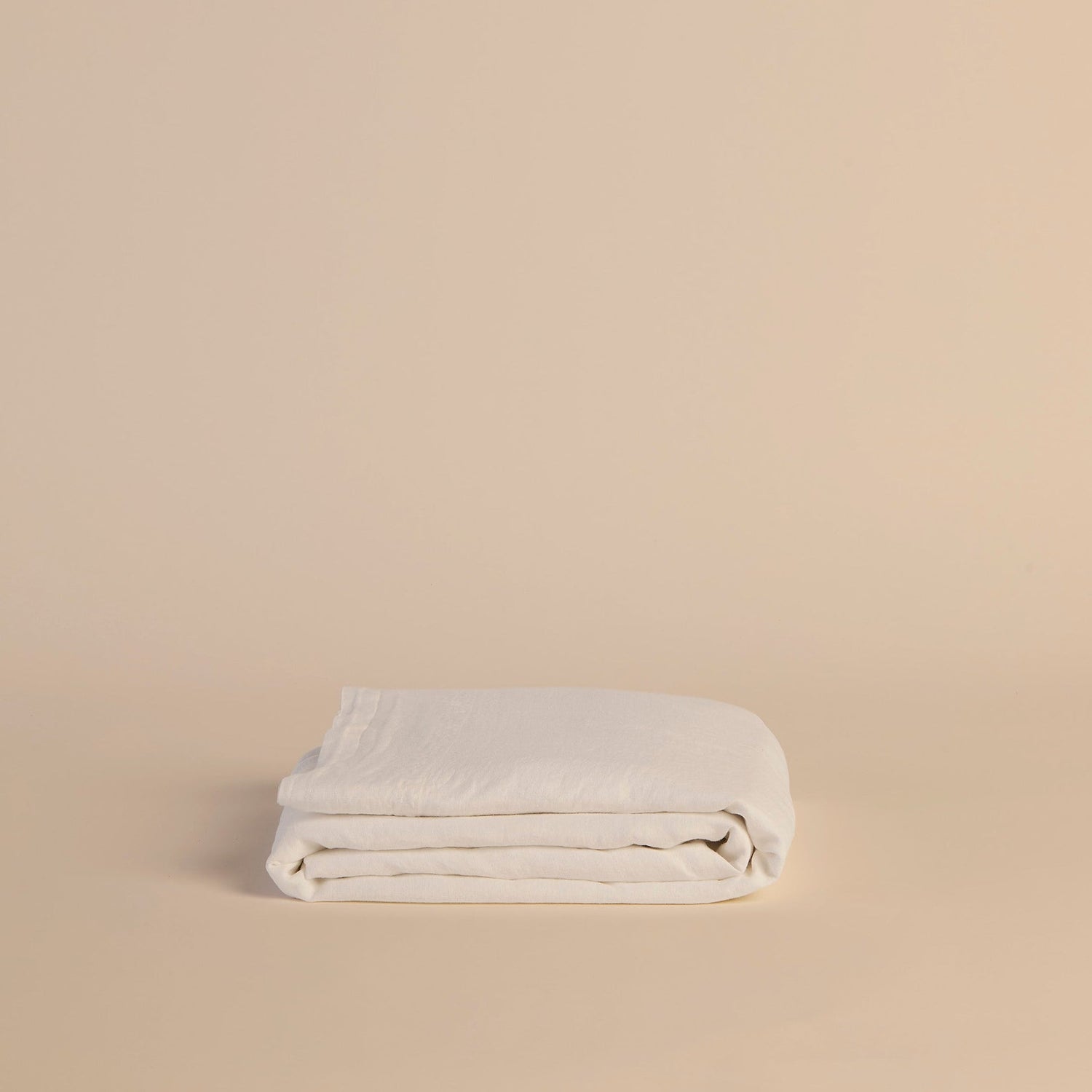 Folded white flat sheet on a beige background