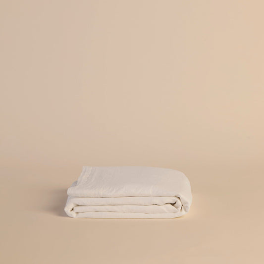 Folded white flat sheet on a beige background