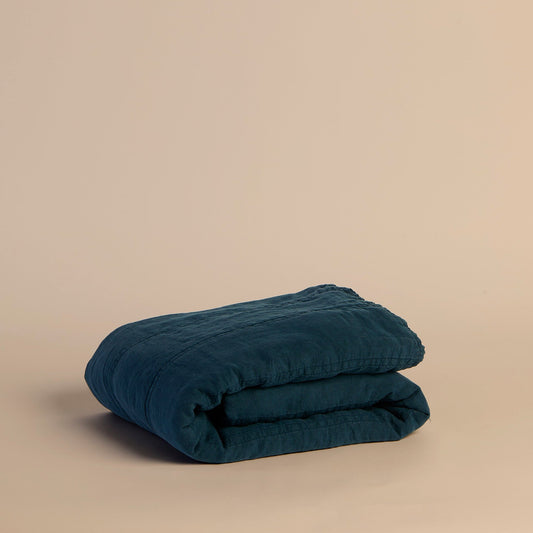 Folded blue quilt on a beige background