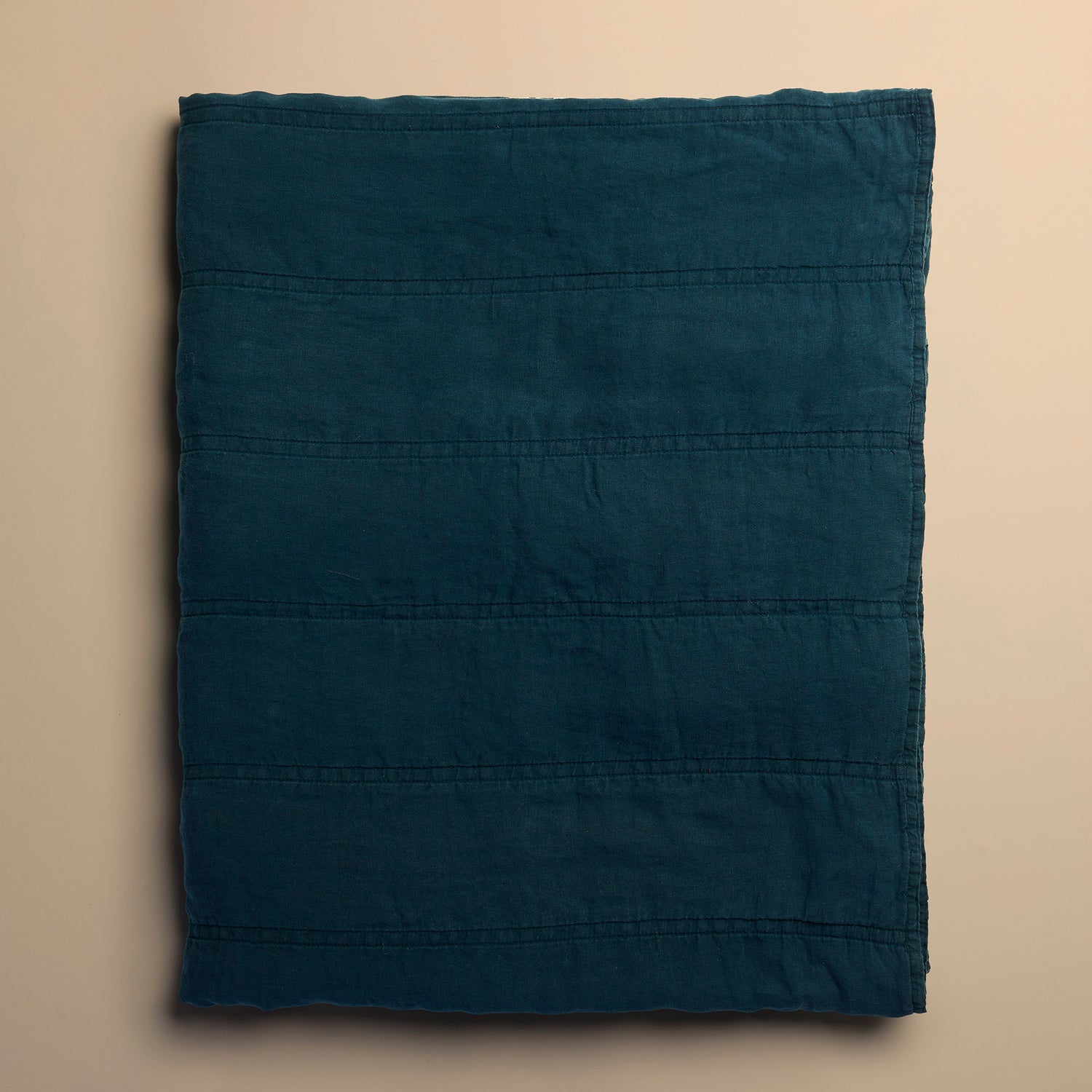 Folded dark blue quilt on a beige background