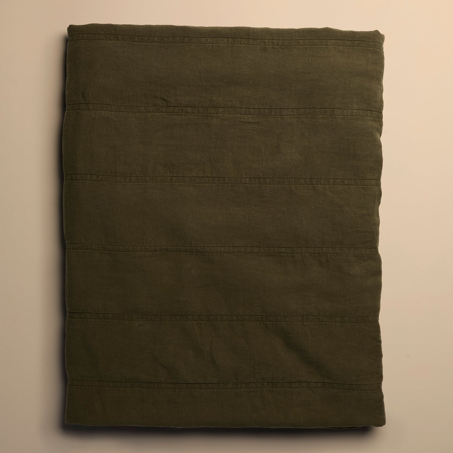 dark green quilt folded on beige background