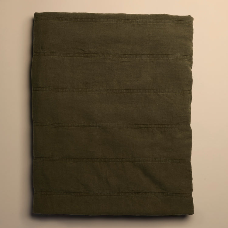 dark green quilt folded on beige background