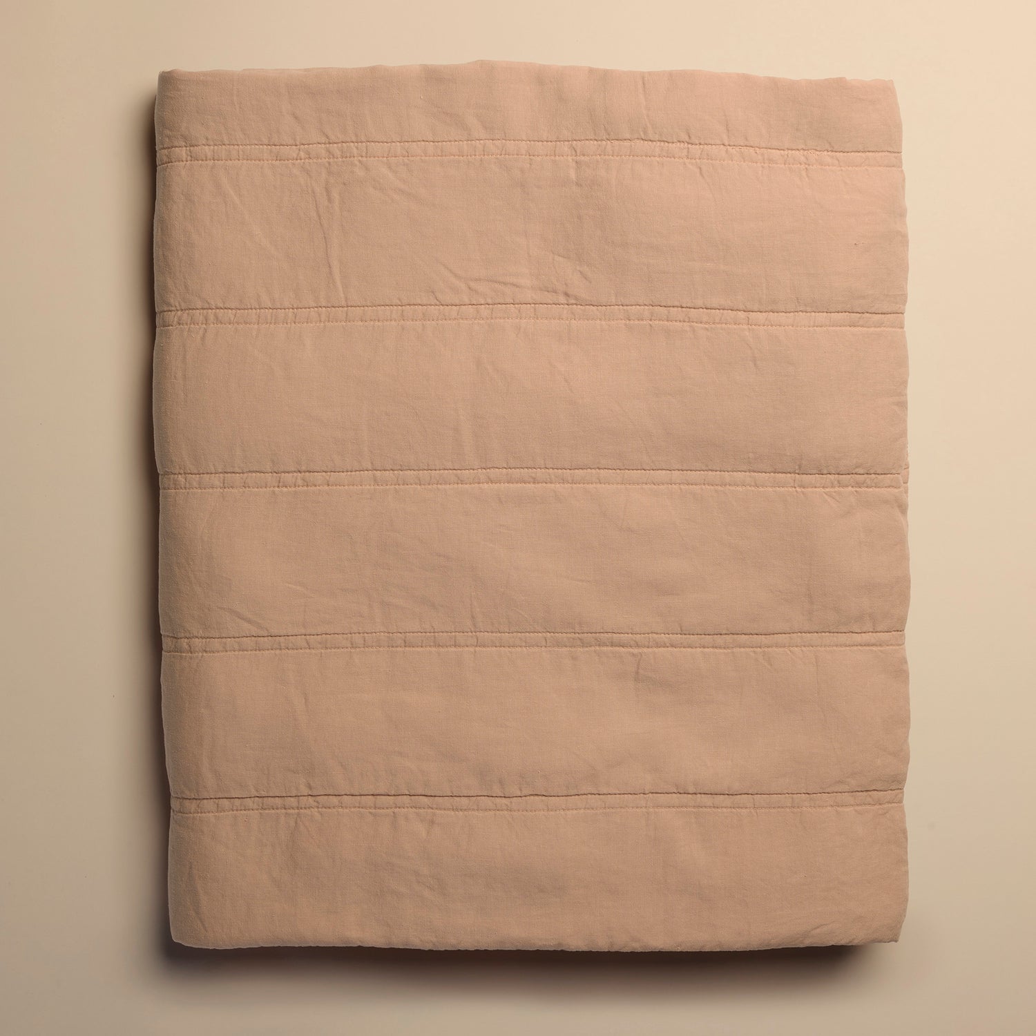 Folded peach quilt on a beige background