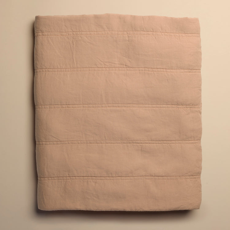 Folded peach quilt on a beige background