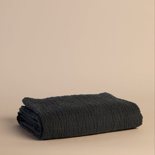 Folded dark blue textured blanket on a beige background