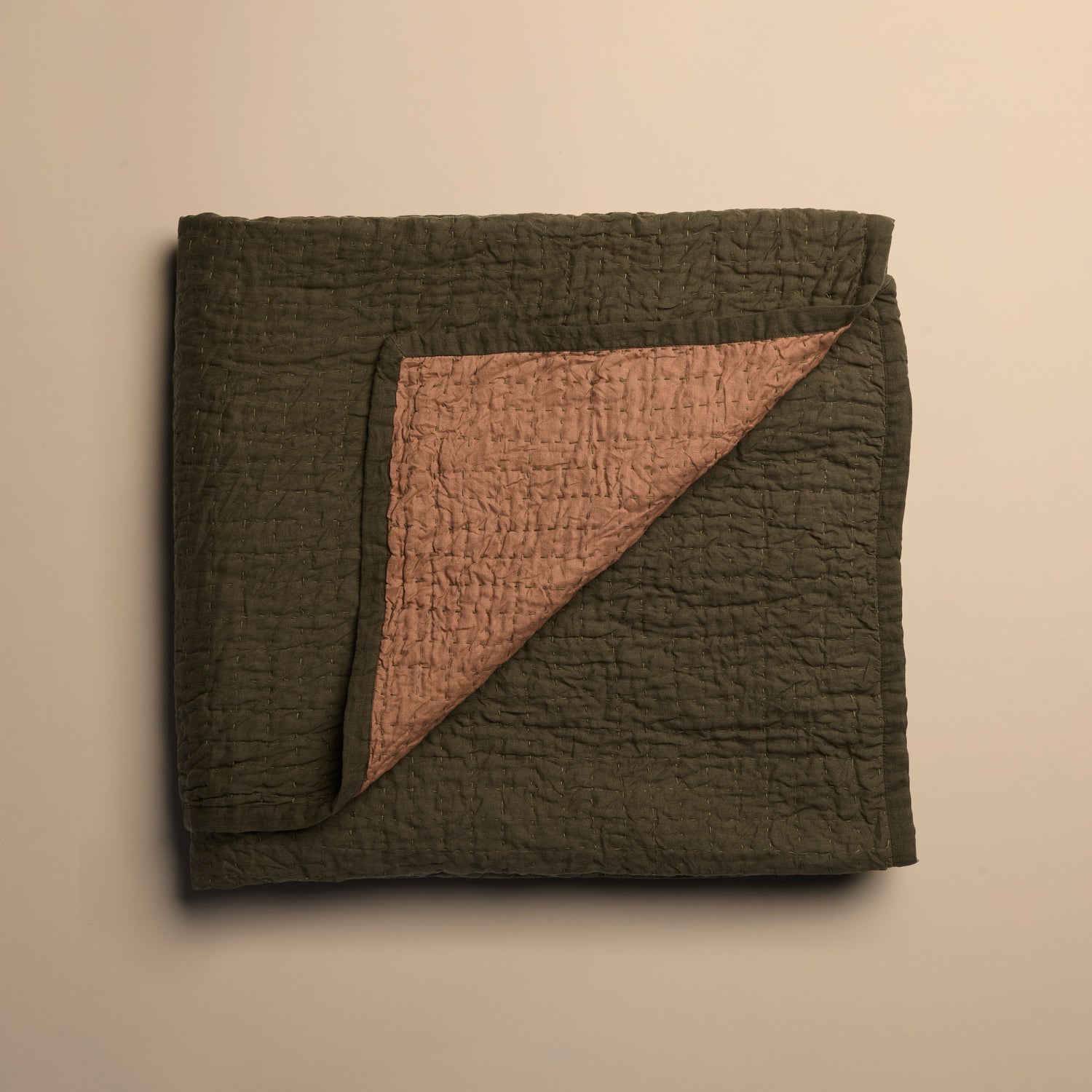 Folded reversible quilt with textured surface on a beige background