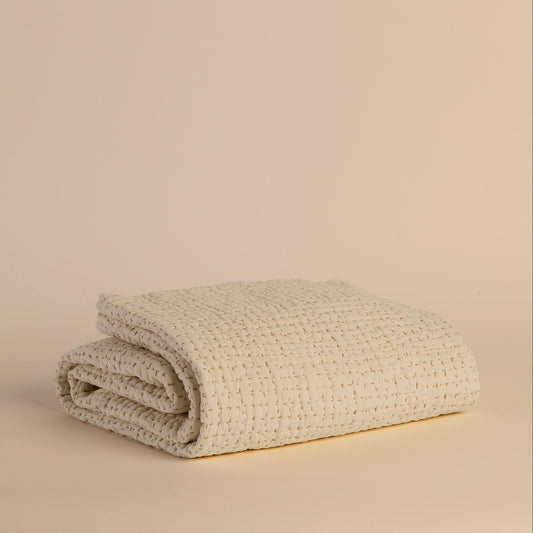 Folded ivory textured blanket on a beige background