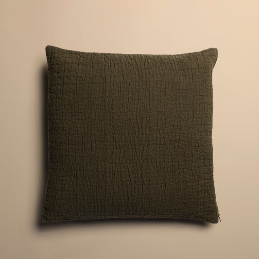 Textured dark green pillow on a beige background