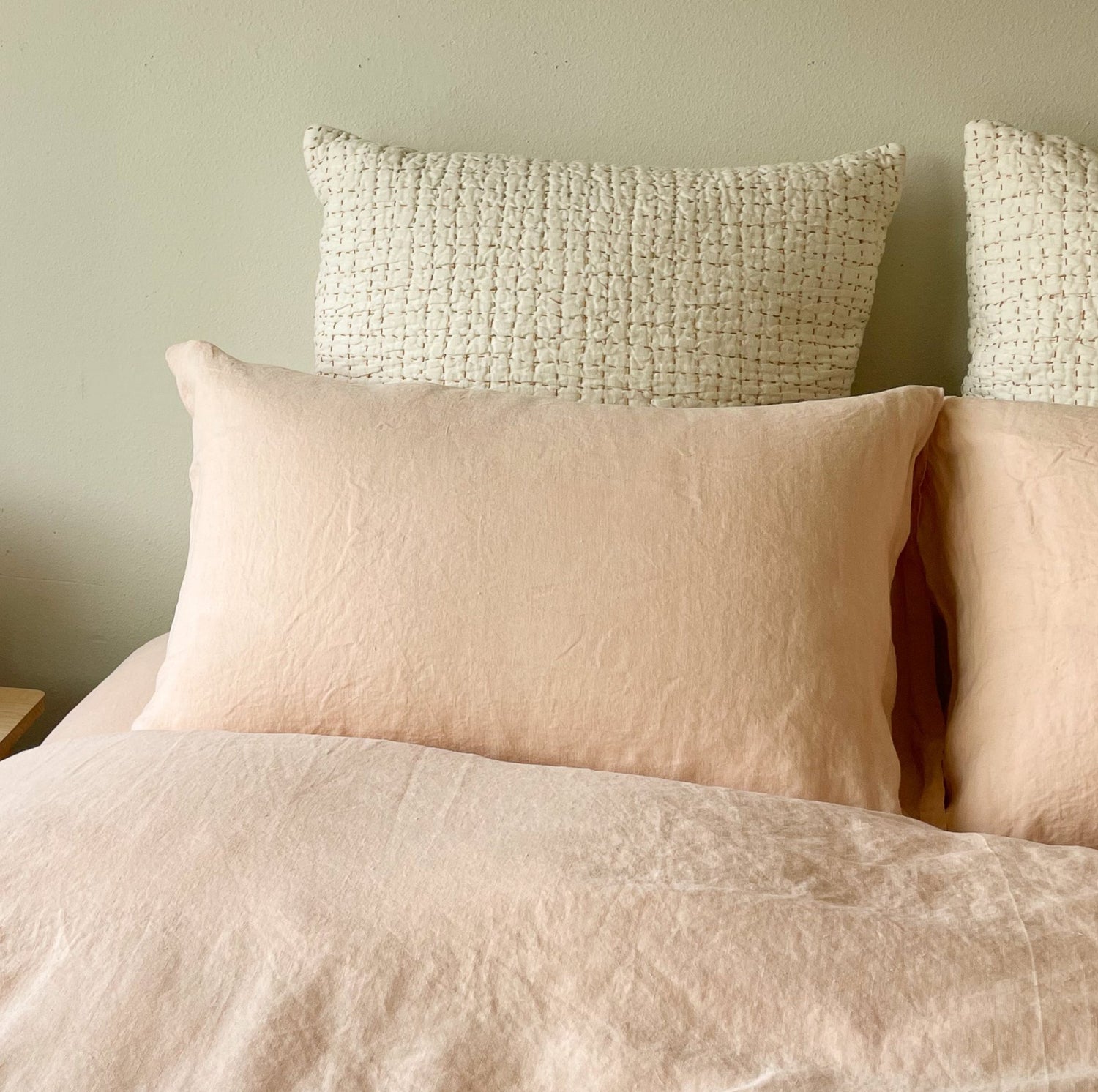 Cozy bed with peach sheets and white hand-stichted quilts
