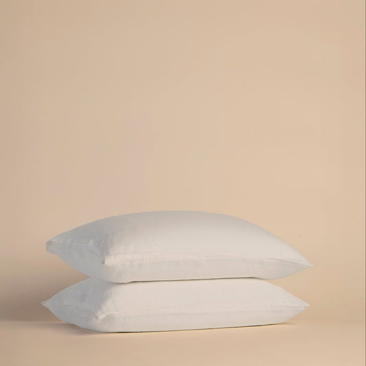 Two white pillows with pillowcases on a beige background