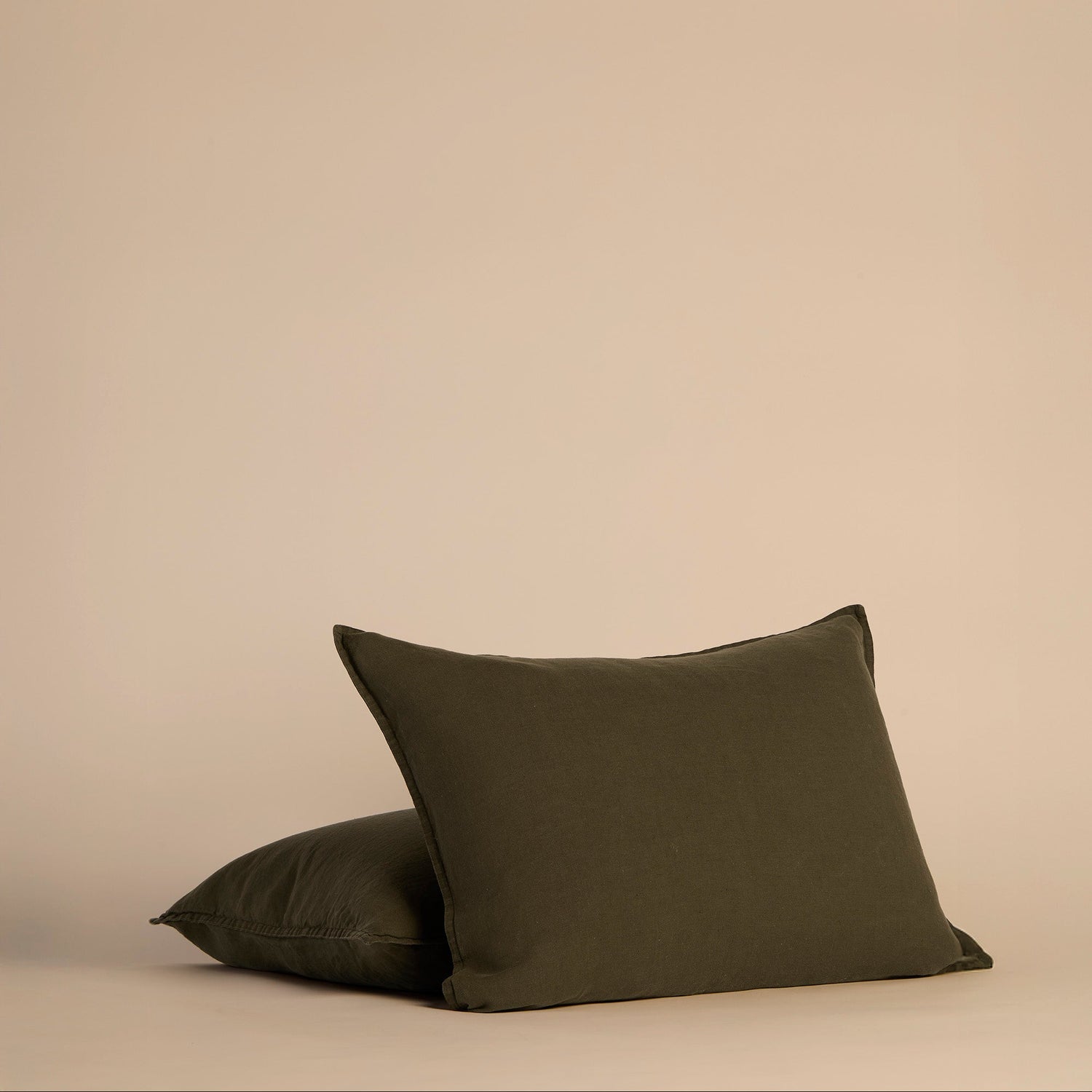 Two dark green shams and pillows on a beige background