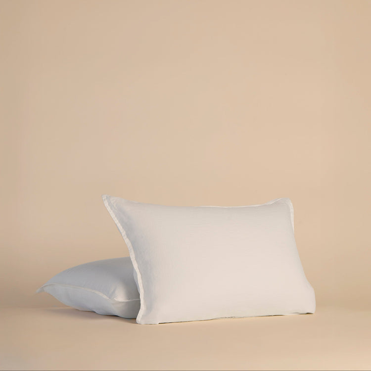 Two white pillowcases and pillows on a beige background
