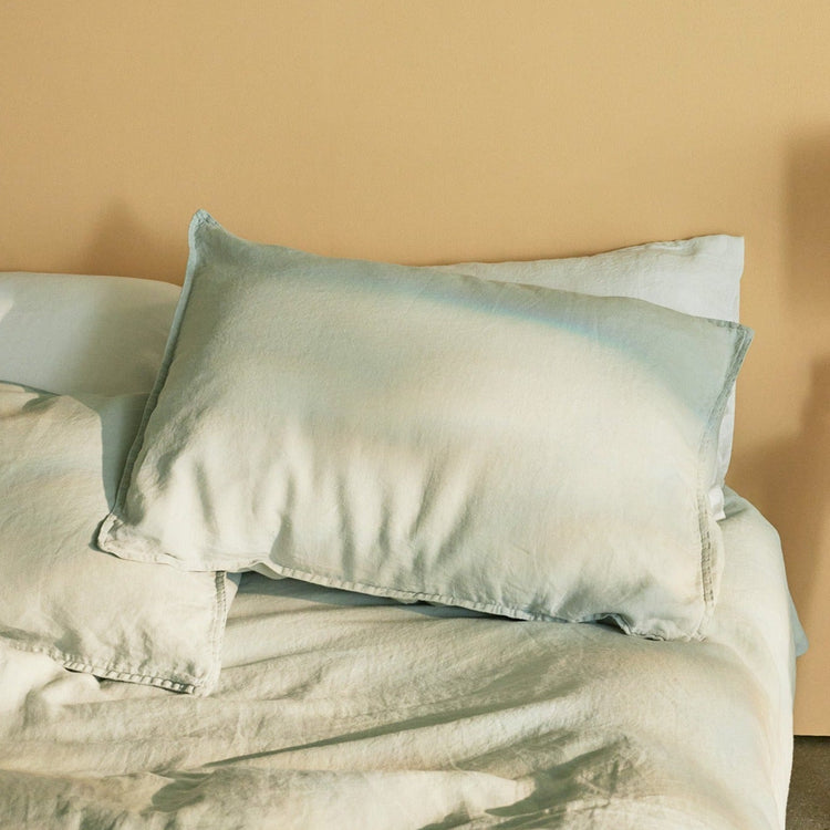 Light blue bedding on simply made bed wiht moody lighting