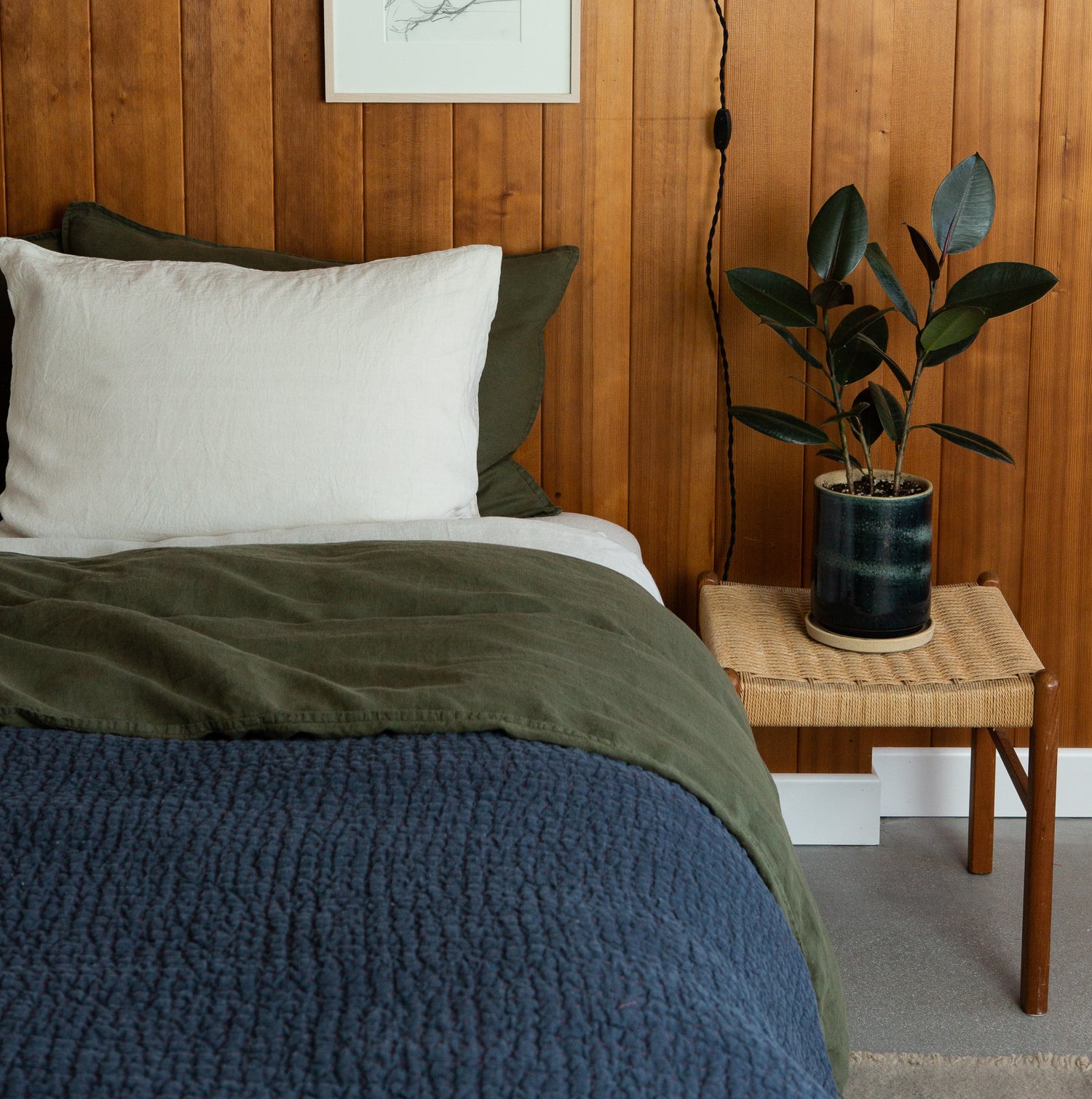 wood panelled room with bed with green and navy blue bedding