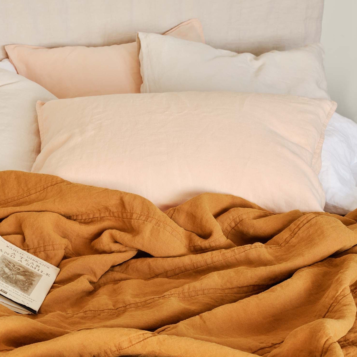 peach shams on cozy bed with multiple pillows and quilts